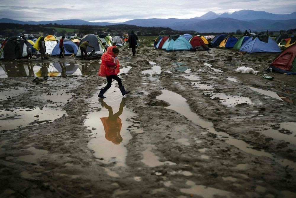 A girl walks in the mud in a makeshift camp at the Greek-Macedonian border, near the Greek village of Idomeni, where thousands of refugees and migrants are stranded by the Balkan border blockade.