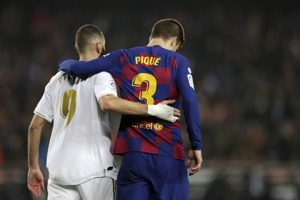 Real Madrid's Karim Benzema and Barcelona's Gerard Pique walk together on the pitch during the match, Dec. 18, 2019. (AP Photo)