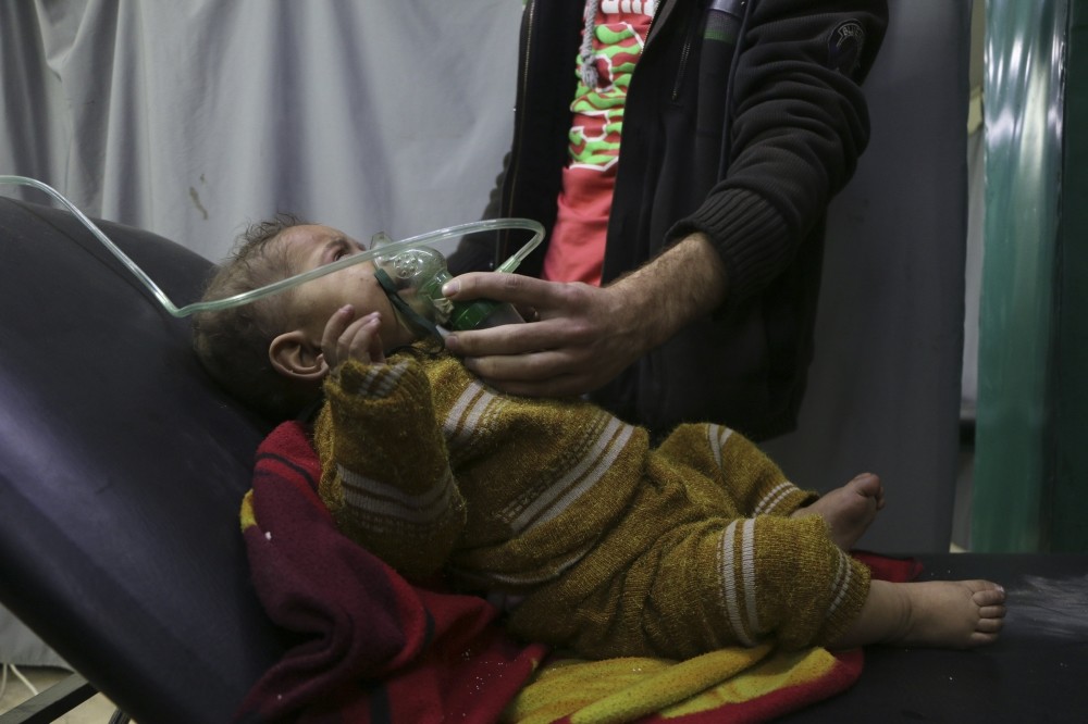 A man gives oxygen through a respirator to a child affected by the chemical attack in Douma.