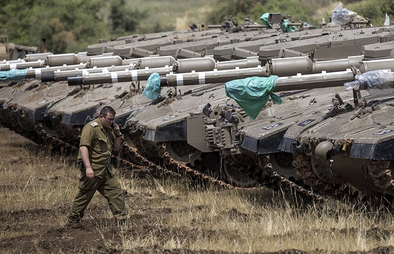 An Israeli soldier walks next to Merkava tanks deployed near the Israeli-Syrian border in the Golan Heights, May 9, 2018. (EPA Photo)