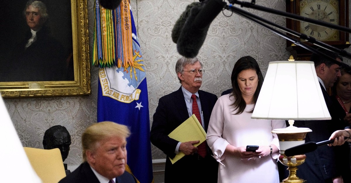U.S. National Security Advisor John R. Bolton (C), White House Press Secretary Sarah H. Sanders (R) and others listen while U.S. President Donald Trump (L) speaks to the press in the Oval Office of the White House, May 13, 2019. 