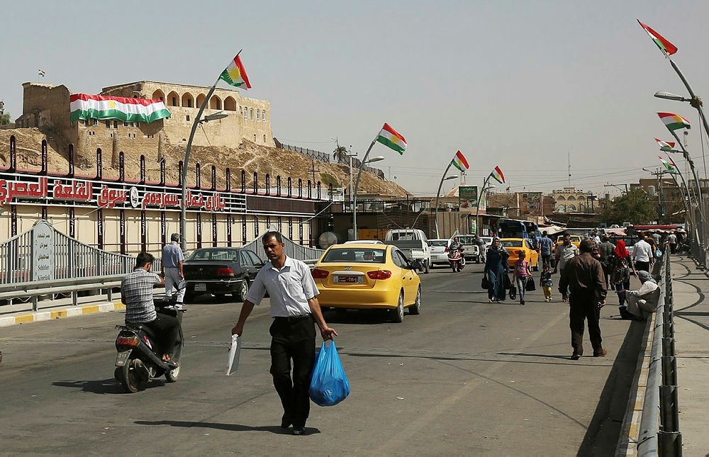 Iraqis walk past Kurdish flags in central Kirkuk on September 24, 2017, on the eve of the independence referendum for the Kurdistan region. (AFP Photo)