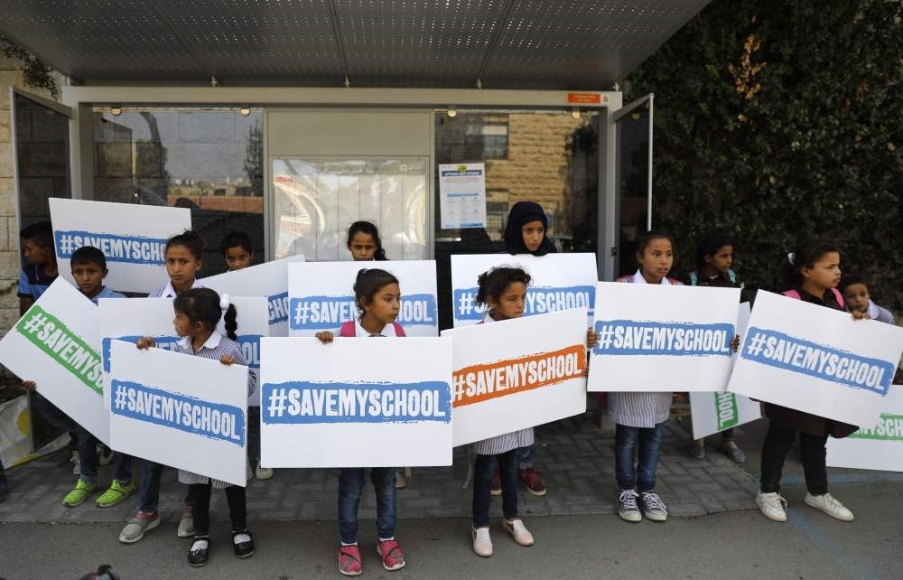 Children from the West Bank Bedouin village of Khan Al Ahmar hold signs with the slogan ,Save my school,, Oct. 4.