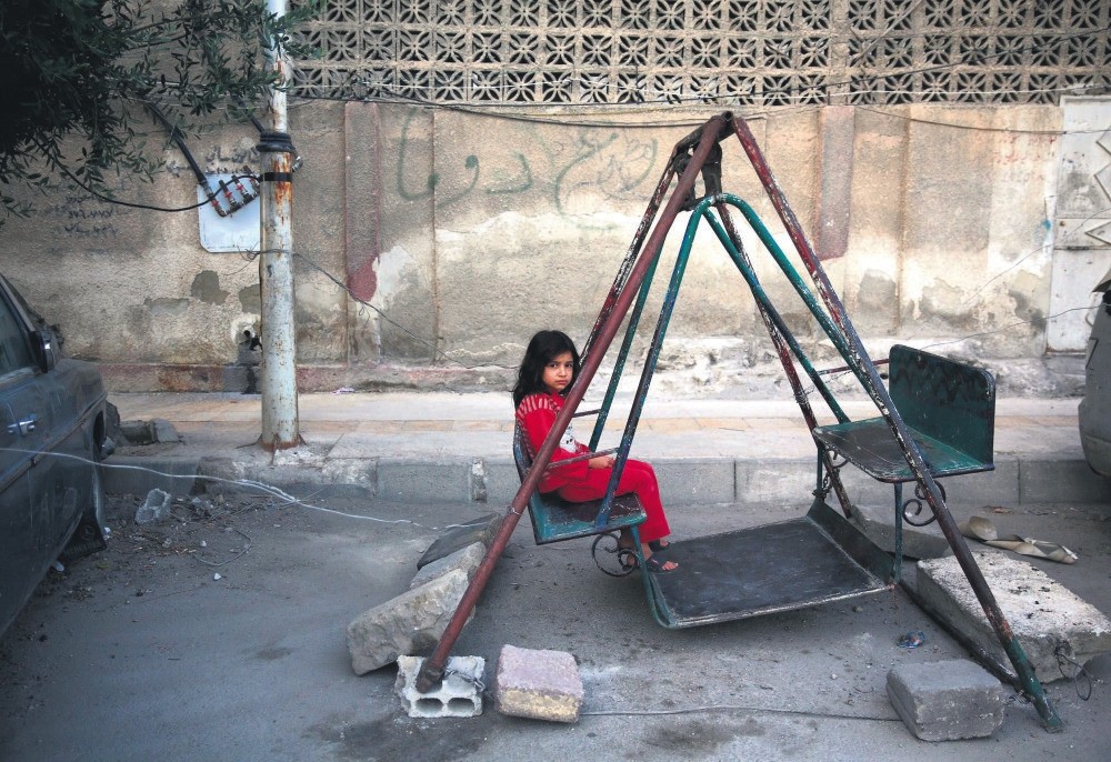 A Syrian girl sits on a swing in eastern Damascus on the first day of the Eid al-Fu0131tr holiday, which marks the end of the Muslim holy fasting month of Ramadan, July 6, 2016.