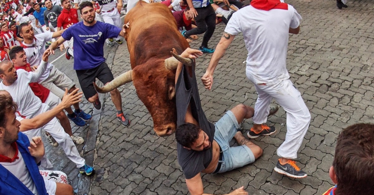 A 'mozo', is caught by the horn of a bull of Miura ranch during the last 'encierro,' or running-with-the-bulls, of the Sanfermines festivities in Pamplona, Spain, 14 July 2019. (EPA Photo)