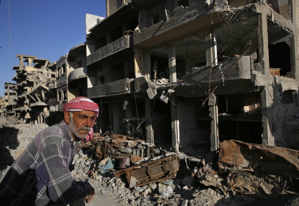 A Syrian man stands between buildings destroyed last summer in fighting between the U.S.-backed YPG and Daesh terrorists, in Raqqa, Syria, April 5.