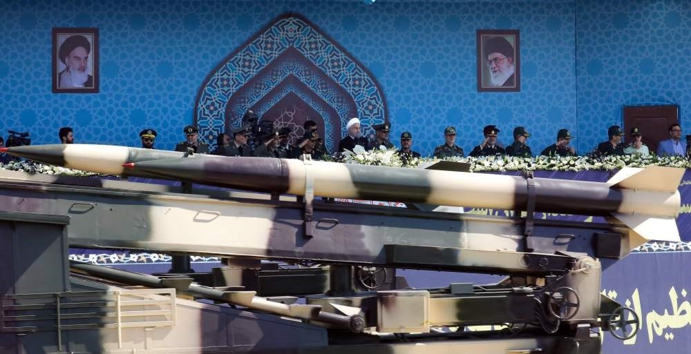 A vehicle carryingan Iranian medium range missile passes by President Rouhani during the annual military parade on Friday.