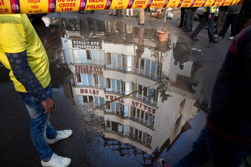 The Arpit Palace Hotel is reflected in a puddle after an early morning fire at the hotel killed more than a dozen people in the Karol Bagh neighborhood of New Delhi, India, Tuesday, Feb.12, 2019. (AP Photo)