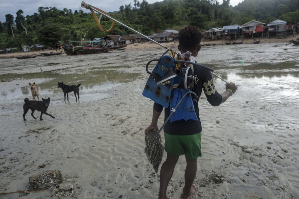 A Moken fisherman, heading home while carrying his fishing gear and a pufferfish he caught in Nyaung Wee village in the Myeik Archipelago, off the coast of southern Myanmar.