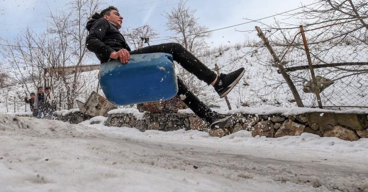 Lacking professional equipment, children utilize plastic cans and makeshift wooden sleds. (AA Photo)