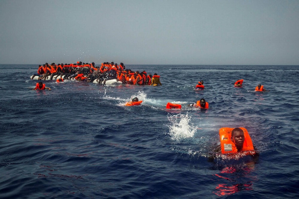 African migrants try to reach a Spanish NGO Proactiva open arms rescue ship from a punctured raft in the Mediterranean Sea, July 23, 2017.