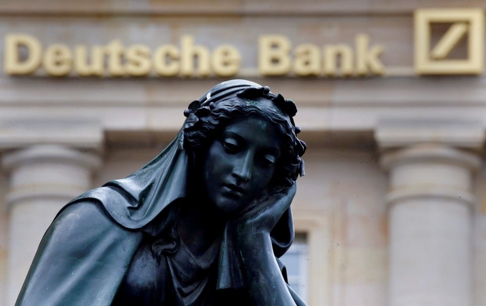 A statue is seen next to the logo of Germany's Deutsche Bank in Frankfurt, Germany, January 26, 2016.