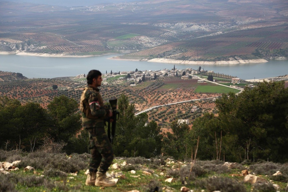 An FSA fighter walks along a ridge overlooking Lake Maydanki, north of the Syrian city of Afrin, after they took control of the nearby village of Ali Bazan from YPG terrorists on March 4.