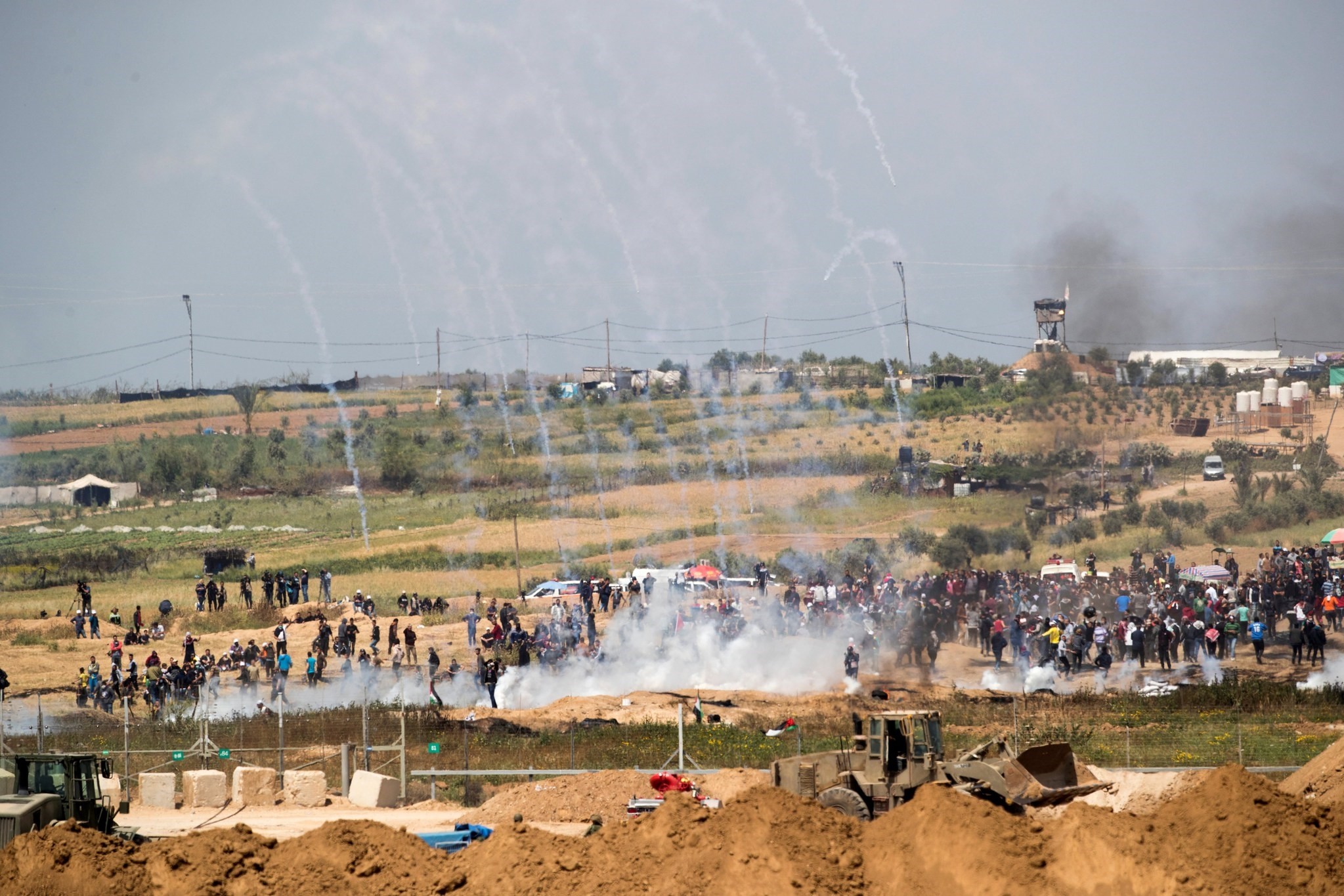 Tear gas canisters fired by Israeli forces fall around Palestinians from Gaza during a protest march at the Israeli Gaza border near Nahal Oz, facing the Gaza neighborhood of Shajaiyaon, April 6, 2018. (EPA Photo)