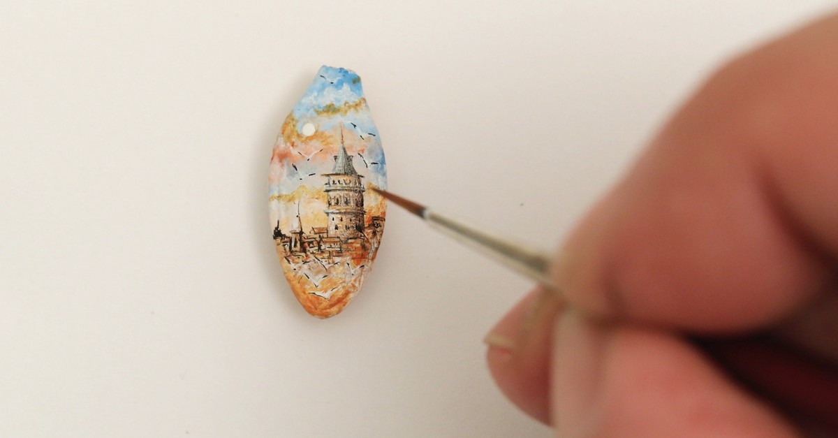 Turkish micro artist Hasan Kale puts the final touches as he paints the Galata Tower on a pumpkin seed.