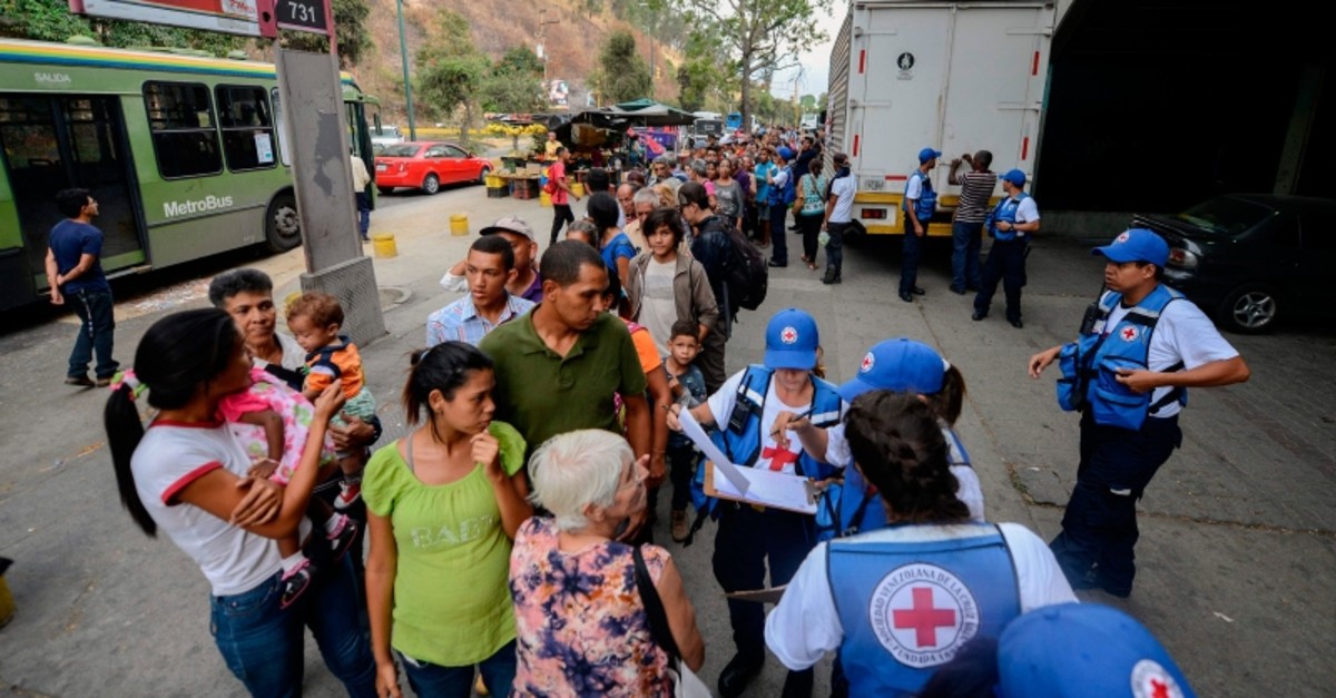 People queue to receive drums to collect water and water purification tablets from members of the Venezuelan Red Cross in Caricuao neighborhood in Caracas, Venezuela, on April 16, 2019. (AFP Photo)