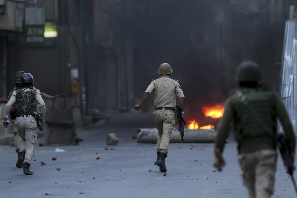 Indian policemen chase Kashmiri protesters during a protest, Srinagar, Indian controlled Kashmir, June 21.