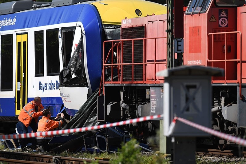 Men in safety vests inspect on May 8, 2018 in Aichach, southern Germany, a passenger train damaged in an accident as it collided with a freight train the day before, killing two people and injuring several others. (AFP Photo)