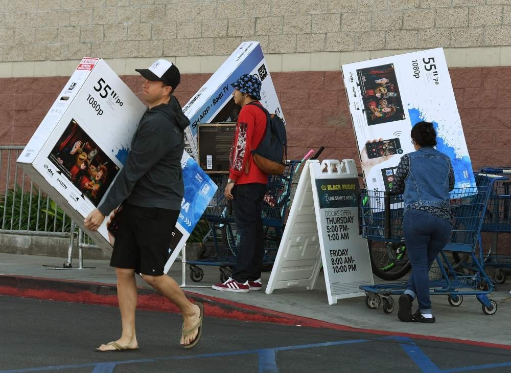 Shoppers with their arms full walk to their cars during Black Friday sales at a Best Buy store, Culver City, Nov. 25, 2016.