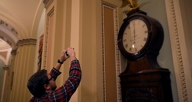 الصحفيون يراقبون ساعة في إحدى ردهات مبنى الكونغرس