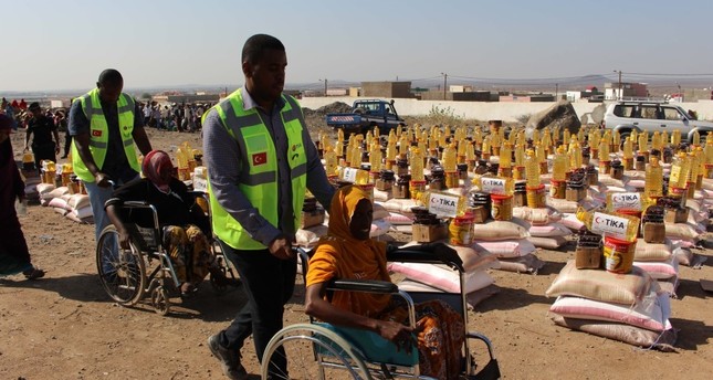 TİKA workers help women in wheelchairs as they arrive to receive aid in Djibouti's Tadjourah region, June 12, 2019.