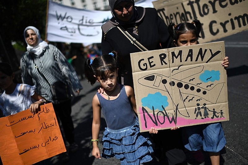 Two children hold a placard picturing a plane as they take part in a demonstration in central Athens outside the German embassy to protest against the limitation of reunification of families in Germany, on August 2, 2017. (AFP Photo)