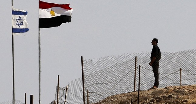 An Egyptian soldier stands near the Egyptian national flag and the Israeli flag at the Taba crossing between Egypt and Israel, about 430 km (256 miles) northeast of Cairo, October 26, 2011. (Reuters Photo)