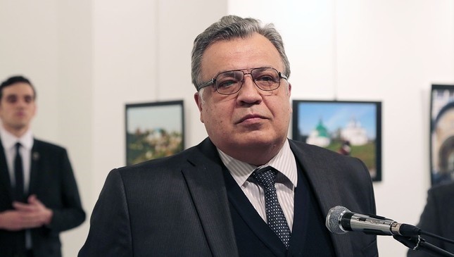 The Russian Ambassador to Turkey Andrei Karlov speaks a gallery in Ankara Monday Dec. 19, 2016. The gunman is seen at rear on the left. (AP Photo)