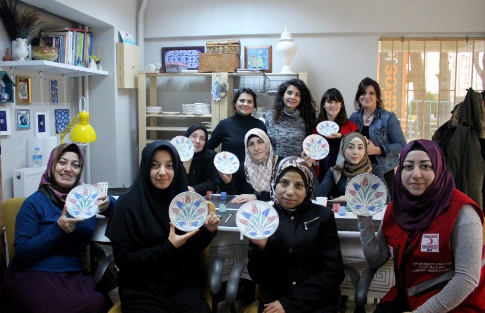 Syrian and Turkish women at the community center pose at a class of plate painting.