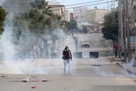People take cover from tear gas grenades during clashes following protests, Kasserine, Dec. 25.