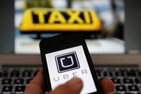 FILE PHOTO: An illustration picture shows the logo of the car-sharing service app Uber on a smartphone next to the picture of an official German taxi sign in Frankfurt, Sept. 15, 2014. (Reuters Photo)