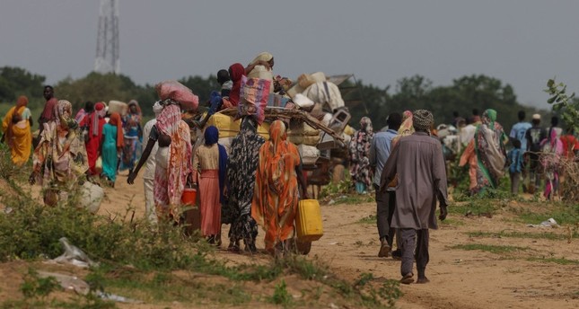 السودانيون ، الذين فروا من الصراع في مورني بمنطقة دارفور السودانية، يسيرون بجوار عربات تحمل أمتعتهم عند عبورهم الحدود بين السودان وتشاد، 2-8-2023 صورة: رويترز