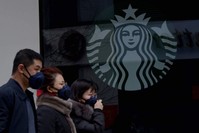 People wearing protective face masks walk past a closed Starbucks coffee shop at a grocery store in Beijing, Jan. 29, 2020. (AFP Photo)