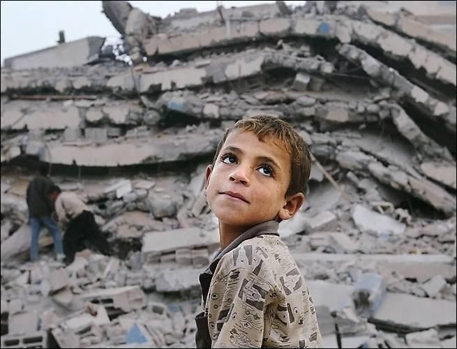 A boy stands  in front of a destroyed building after the earthquake, which killed thousands of people.