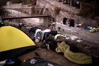 A man sleeps near a tent on the street along with other refugees and migrants after arriving on the Greek island of Lesbos by crossing the Aegean Sea from Turkey, Oct. 7, 2015.