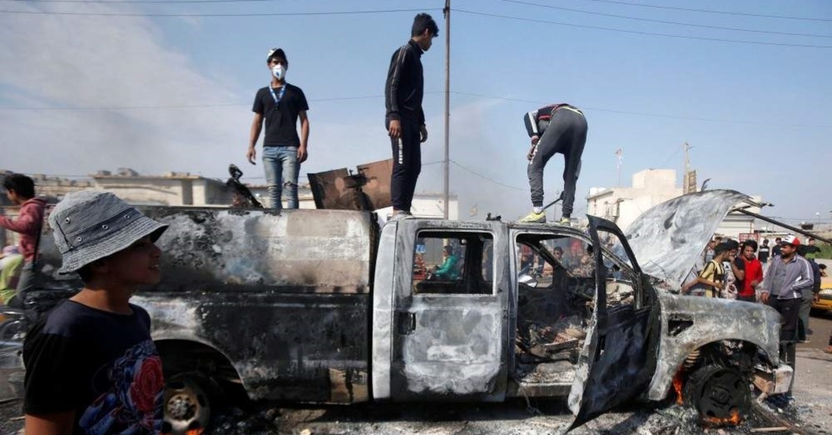 Protesters stand on a military vehicle belonging to the Iraqi security forces after burning it, Basra, Nov. 24, 2019. (REUTERS Photo)