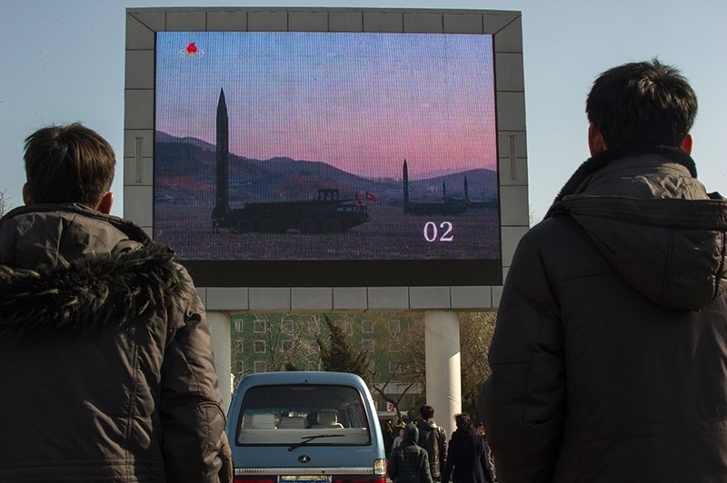People watch news footage of a missile launch on a giant television screen outside the main railway station in Pyongyang on March 7, 2017. (AFP Photo)