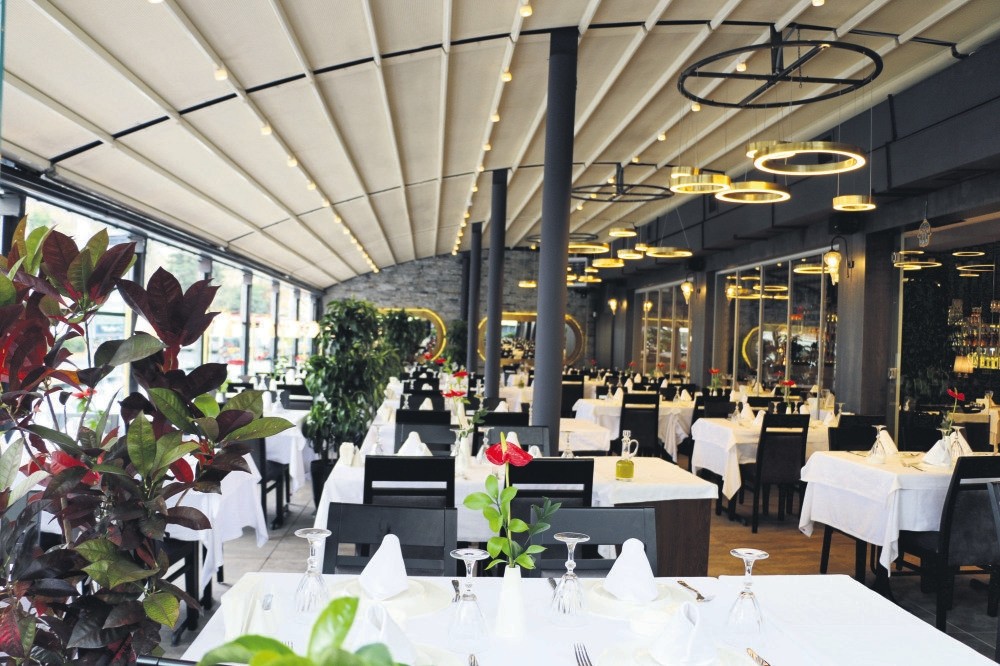 Yu00fcksel Balu0131k has brass lampshades, modern chandeliers, walls with mirrors and fresh orchids on the tables. 