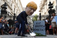 A demonstrator, wearing a mask depicting Britain's Prime Minister Boris Johnson, and a mock gravestone inscribed with the words ,RIP British Democracy, protests outside the gates to Downing Street in central London on August 28, 2019. (AFP Photo)