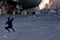 An anti-government protester uses a slingshot to fire a stone at security forces during clashes near Khilani Square, Baghdad, Feb. 3, 2020. (AP Photo)