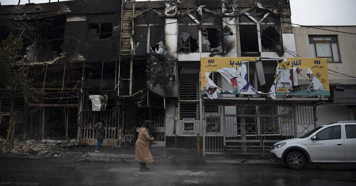 A pedestrian walks past buildings that were burned down during protests in Karaj, Iran, Nov. 18, 2019. (AP Photo)