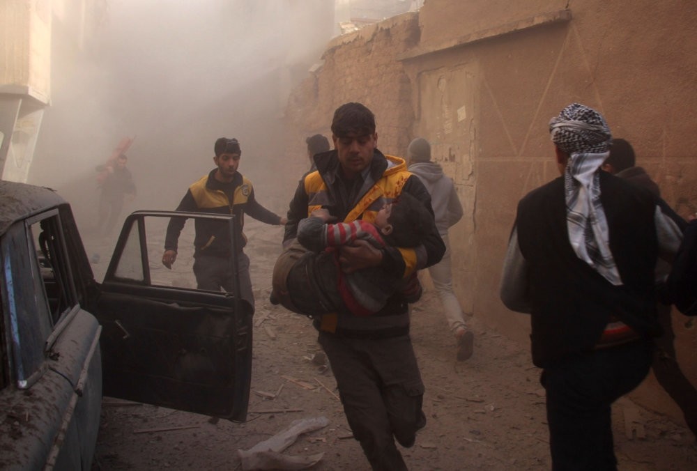 Members of the Syrian a volunteer civil defense group the White helmets, evacuate wounded people following airstrikes in the Eastern Ghouta region on the outskirts of the capital Damascus, Jan. 8. 