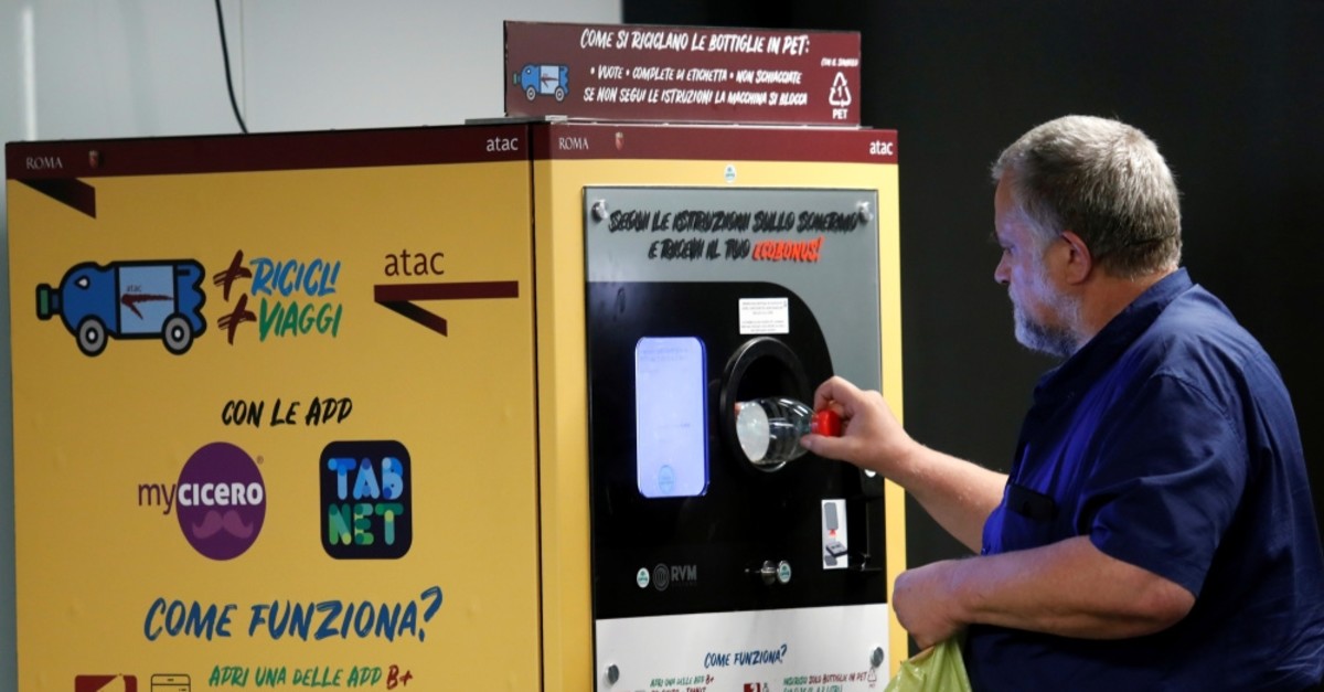 A man puts a plastic bottle into a recycling machine in San Giovanni metro station in Rome, Italy.