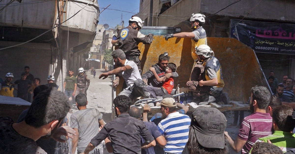 A man carries a child rescued from a building destroyed in a Syrian regime airstrike in Idlib, May 27, 2019.