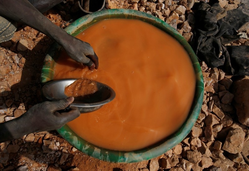 An artisanal miner pans for gold using a plastic wash basin and metal pan at an unlicensed mine near the city of Doropo, Ivory Coast, February 13, 2018