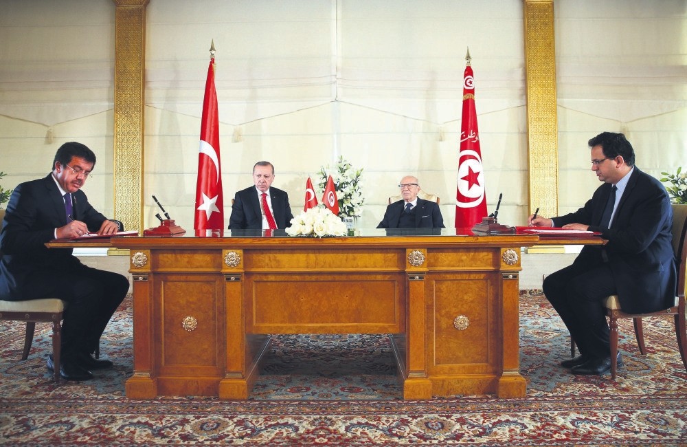 Accompanying President Erdou011fan, second from left, in Tunisia, Economy Minister Nihat Zeybekci (L) signed an agreement on the Encouragement and Mutual Protection of Investments with Tunisian counterpart Fadhel Abdelkefi (R), Tunis, Dec. 27.