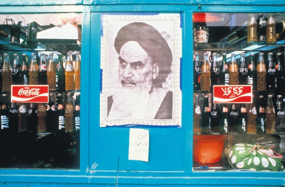 A poster of Ayatollah Ruhollah Khomeini, the founder of the Islamic Republic of Iran, in a shop window next to bottles of Coca-Cola, Tehran, Iran, Jan. 1, 1979.