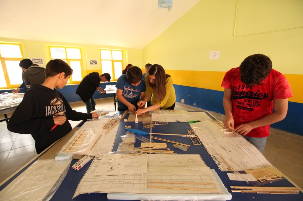 Students of u015eehit Arif u00c7etin Secondary School work on their model plane project under the supervision of their teacher.