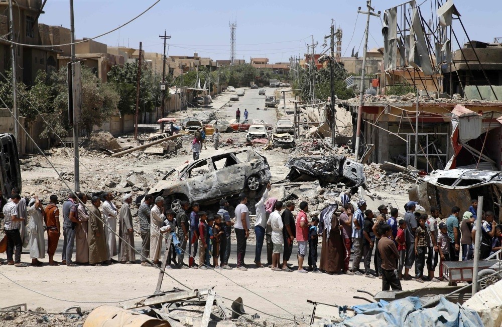 Syrians walk along a severely damaged road in the northeastern city of Deir ez-Zor.