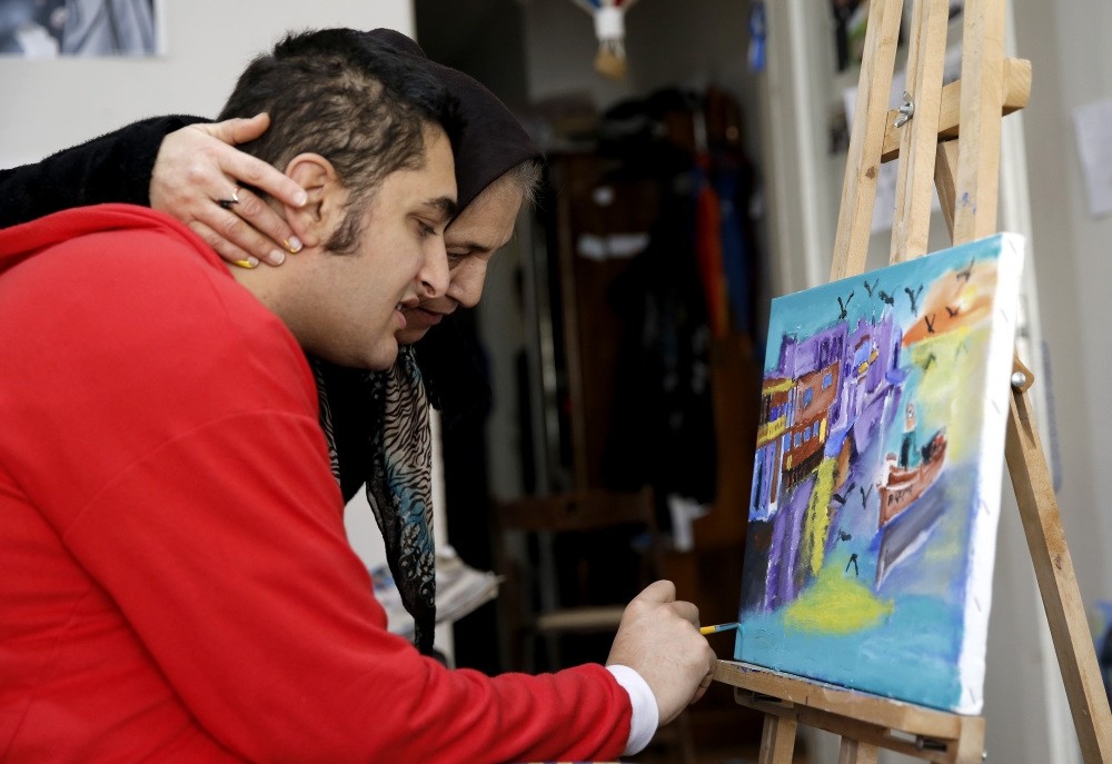 Erkan Ku0131zu0131ldau011f, an autistic artist, draws a painting at home as his mother looks at it. Unofficial numbers show there are more than 1 million people affected by autism in Turkey.